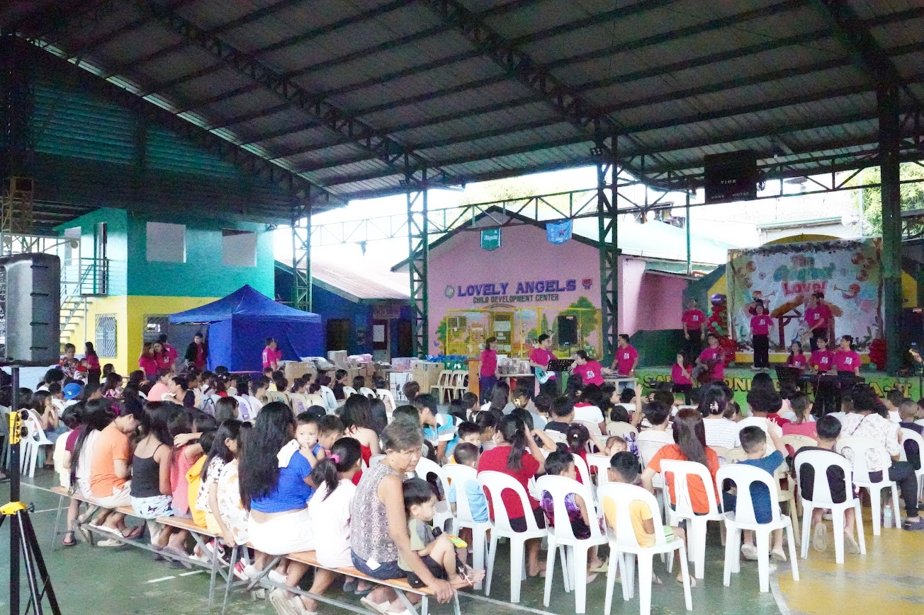 The court fills with families for the morning session, the stage at the far end.