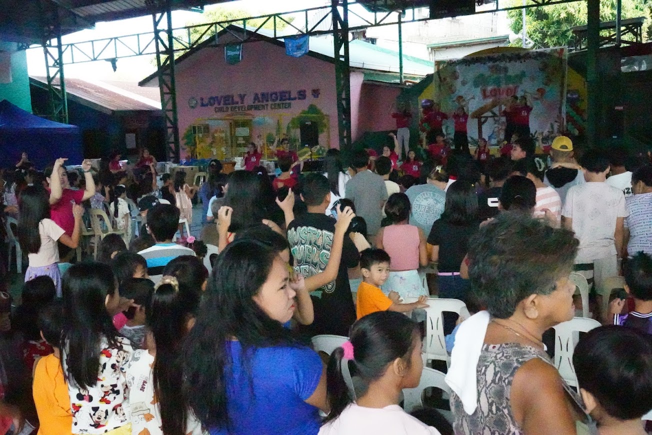 The band plays beneath "The Greatest Love!" as the children gather in front.