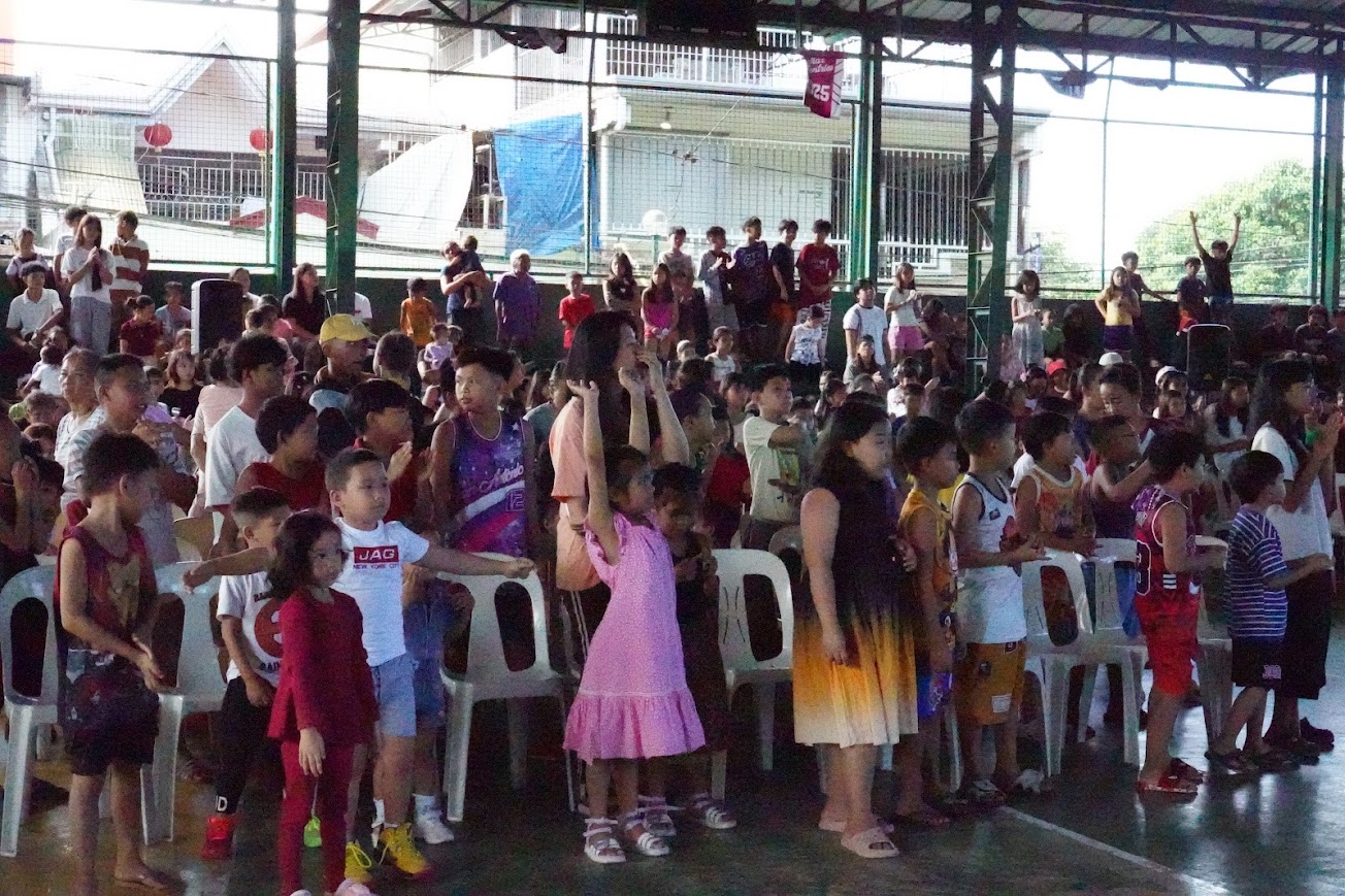 A boy claps along in the front row as the crowd sings.