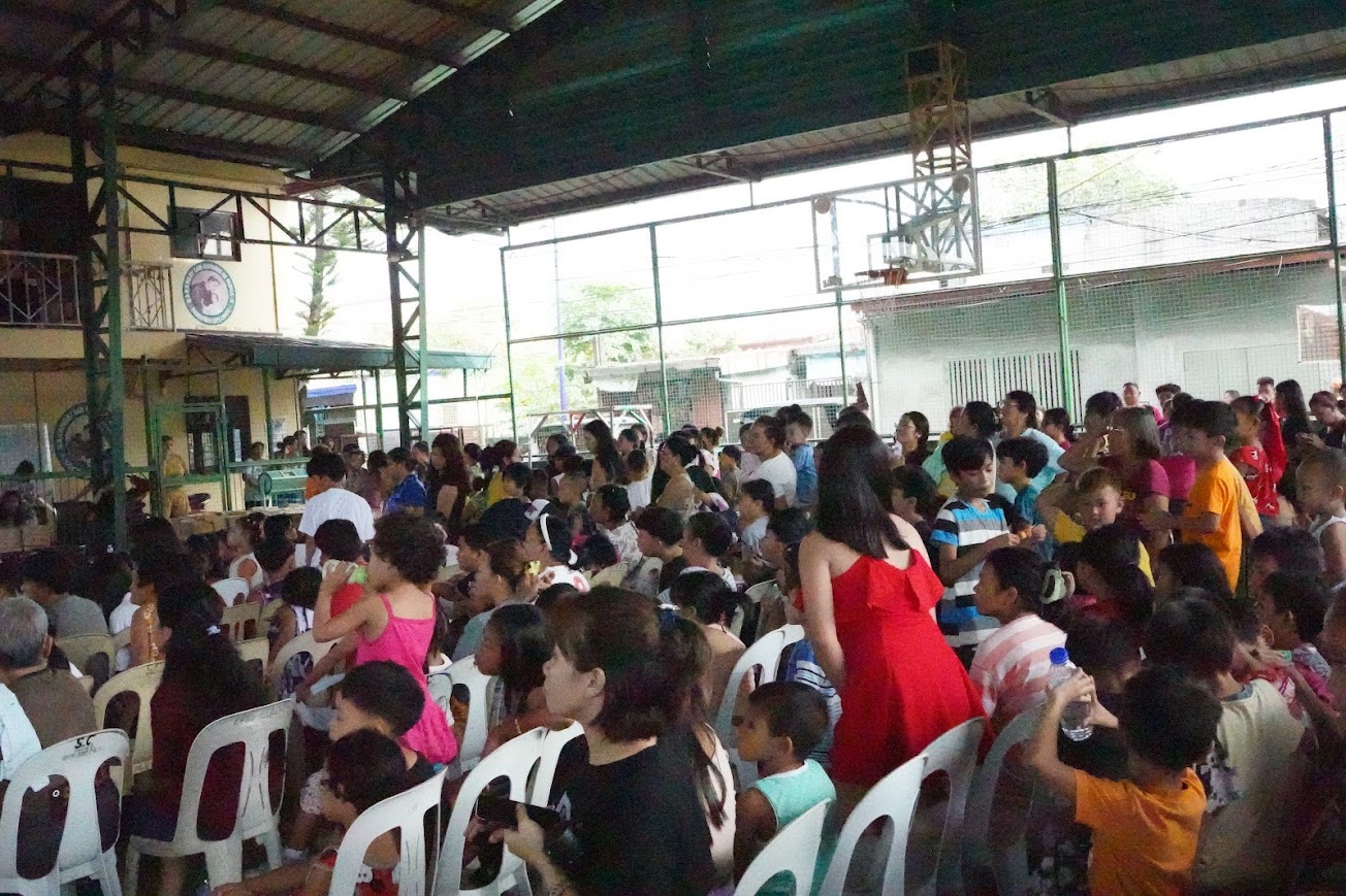 A children's group performs on stage beneath "The Greatest Love!".