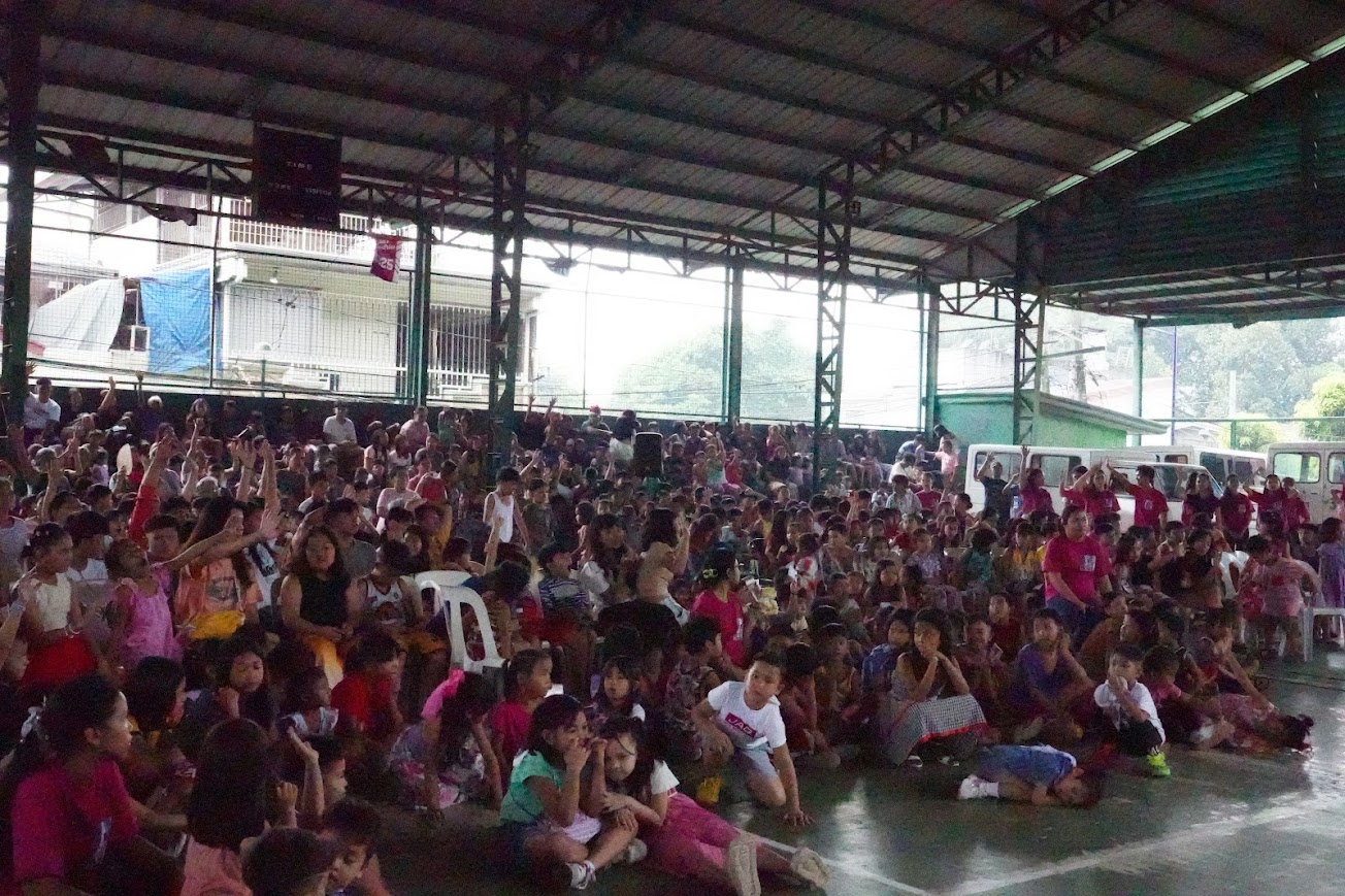Two team members lead the children in motions, arms raised.