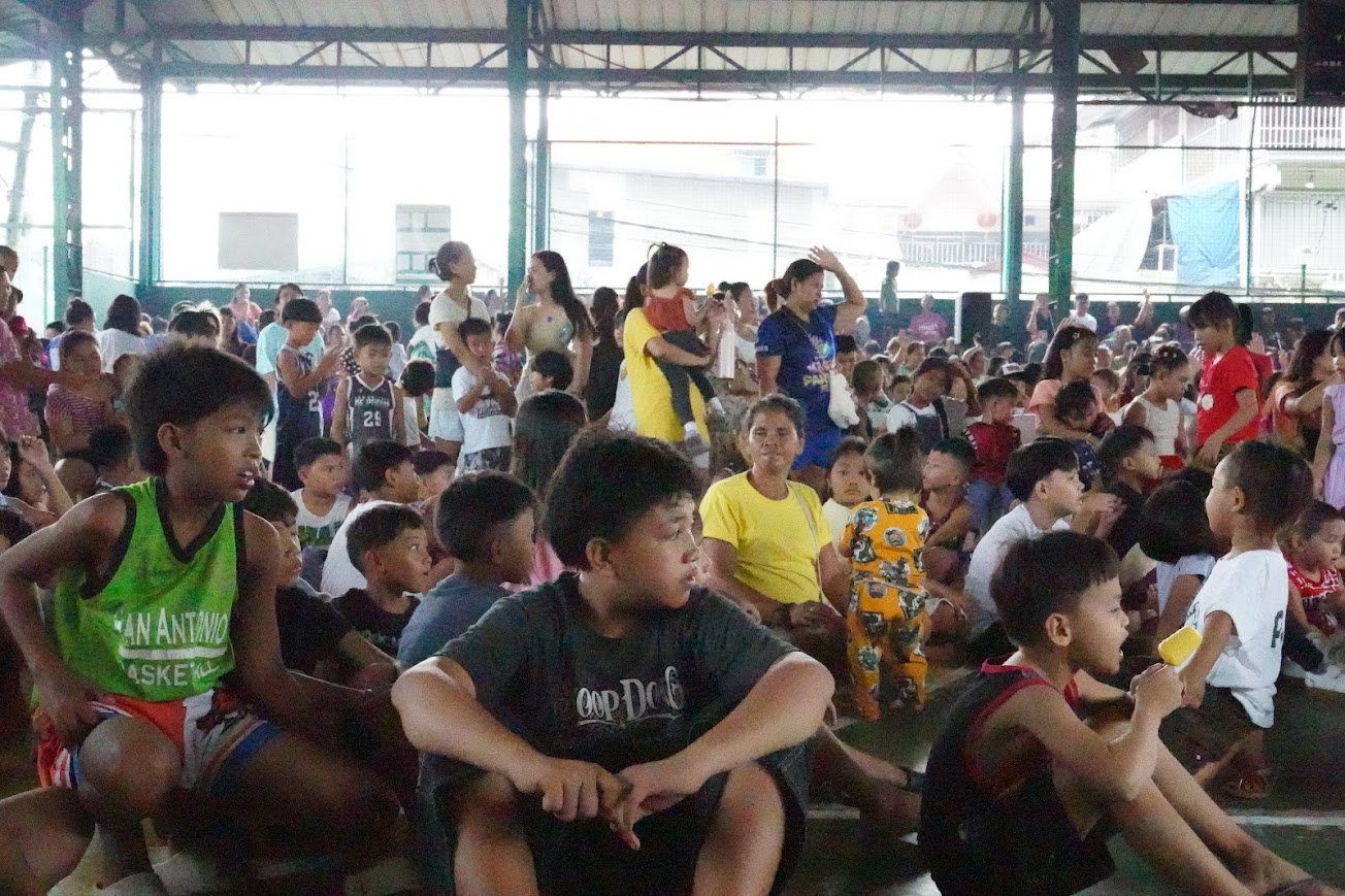 The children follow along, hands up across the whole court.