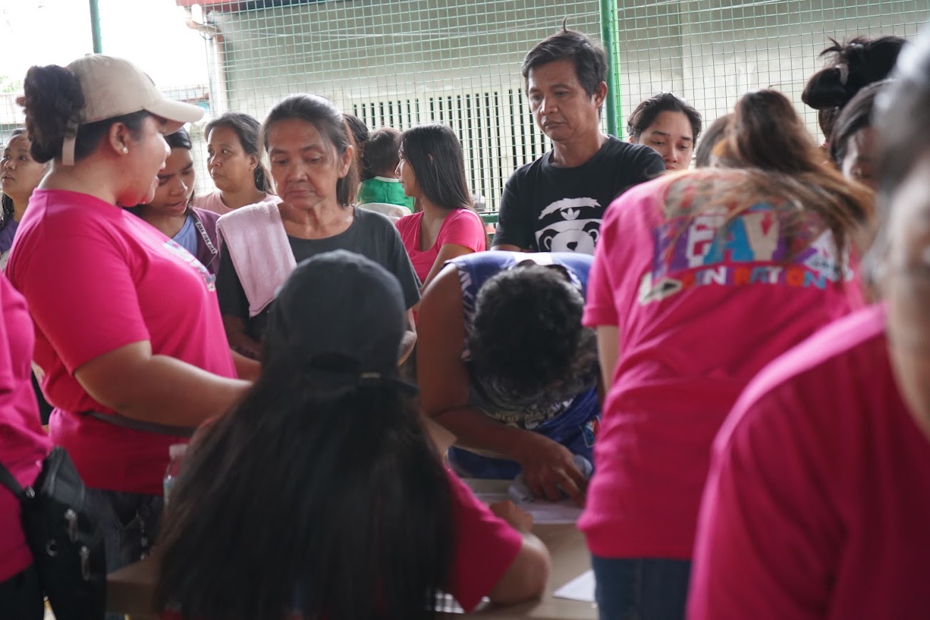 A community member signs the registration sheet, wristbands ready.
