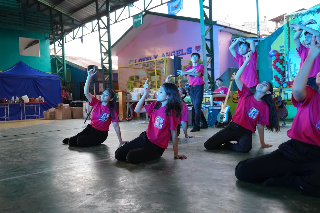 The youth dance team performs in a line, arms outstretched.