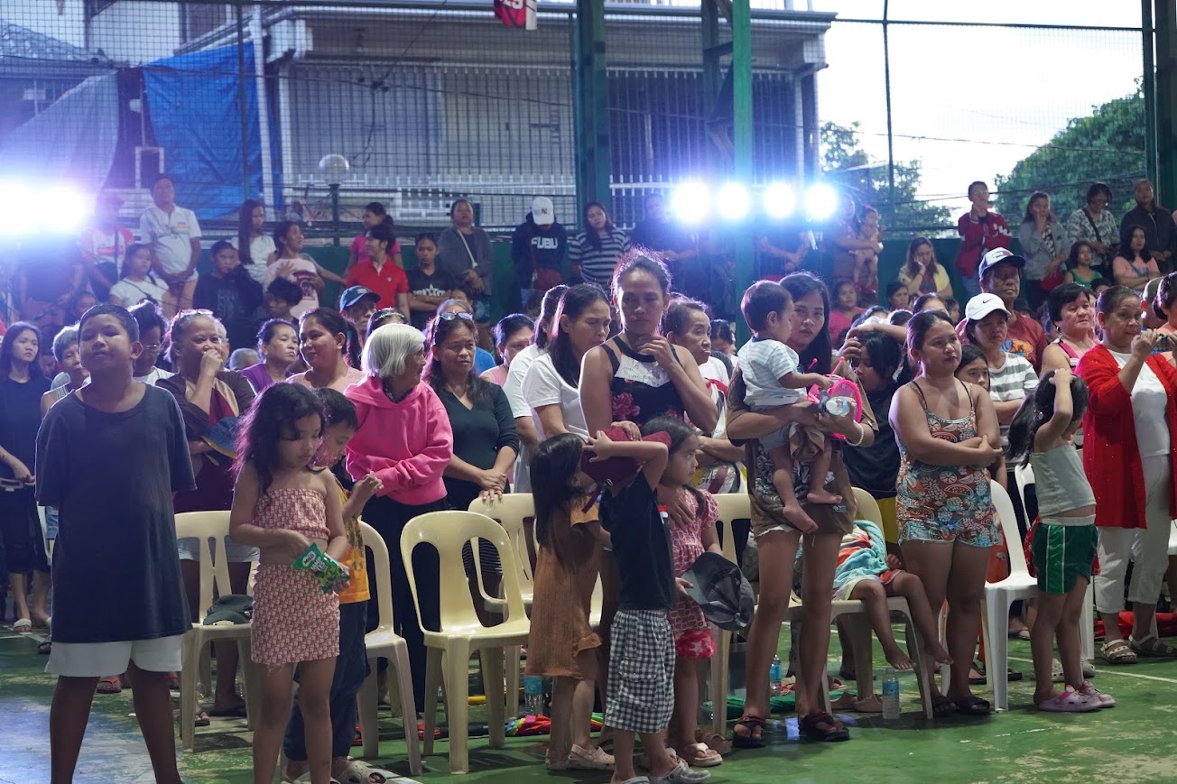 Community members standing in prayer at the start of the gathering.