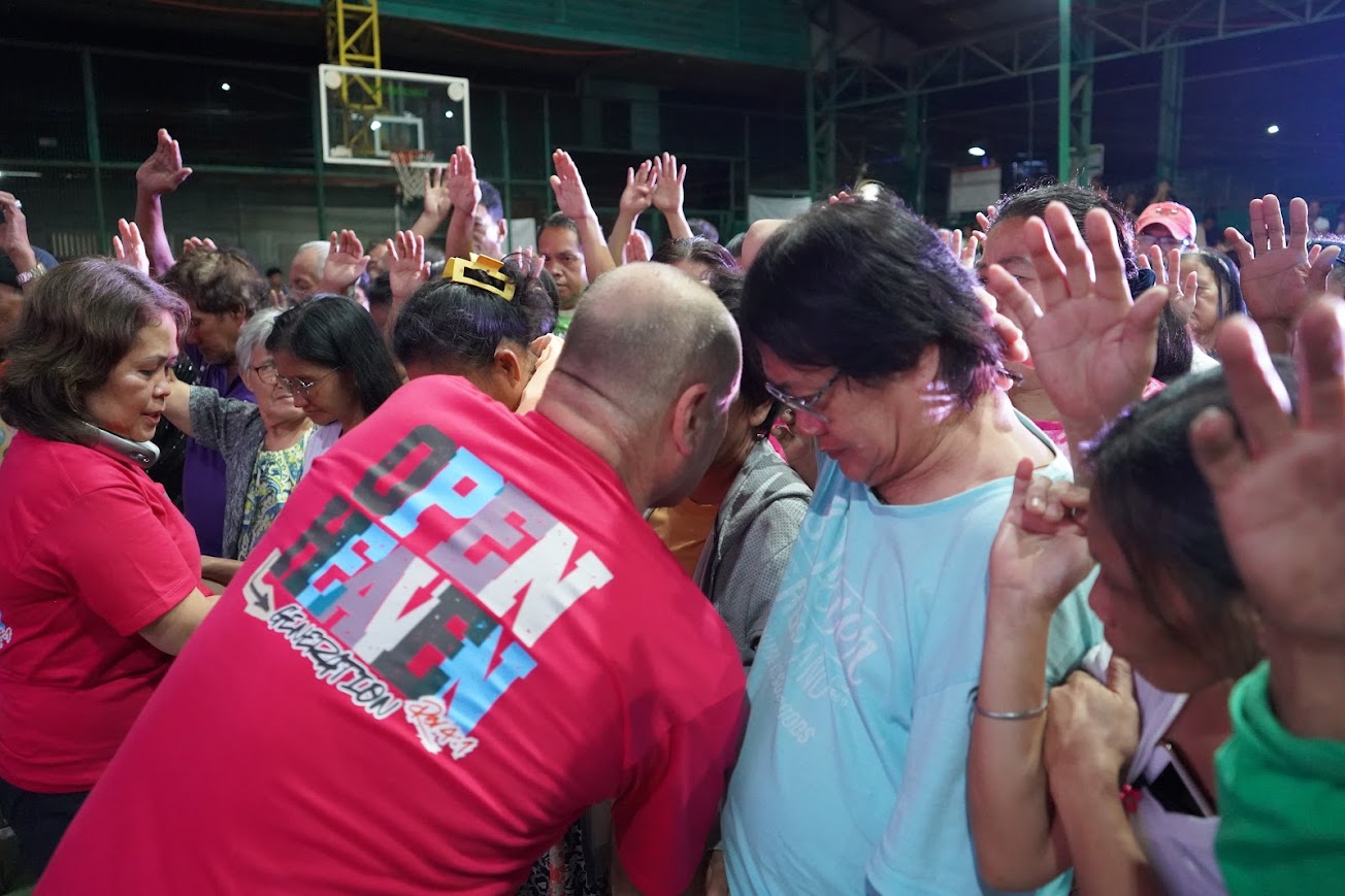 Team members lean in to pray, hands raised across the crowd.