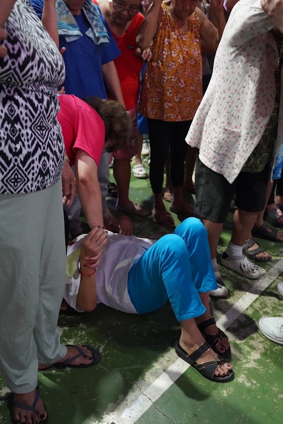 A team member prays over a mother holding her infant.