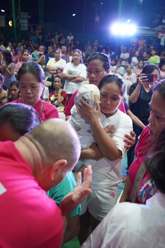 Community members gather around a woman resting on the court floor.