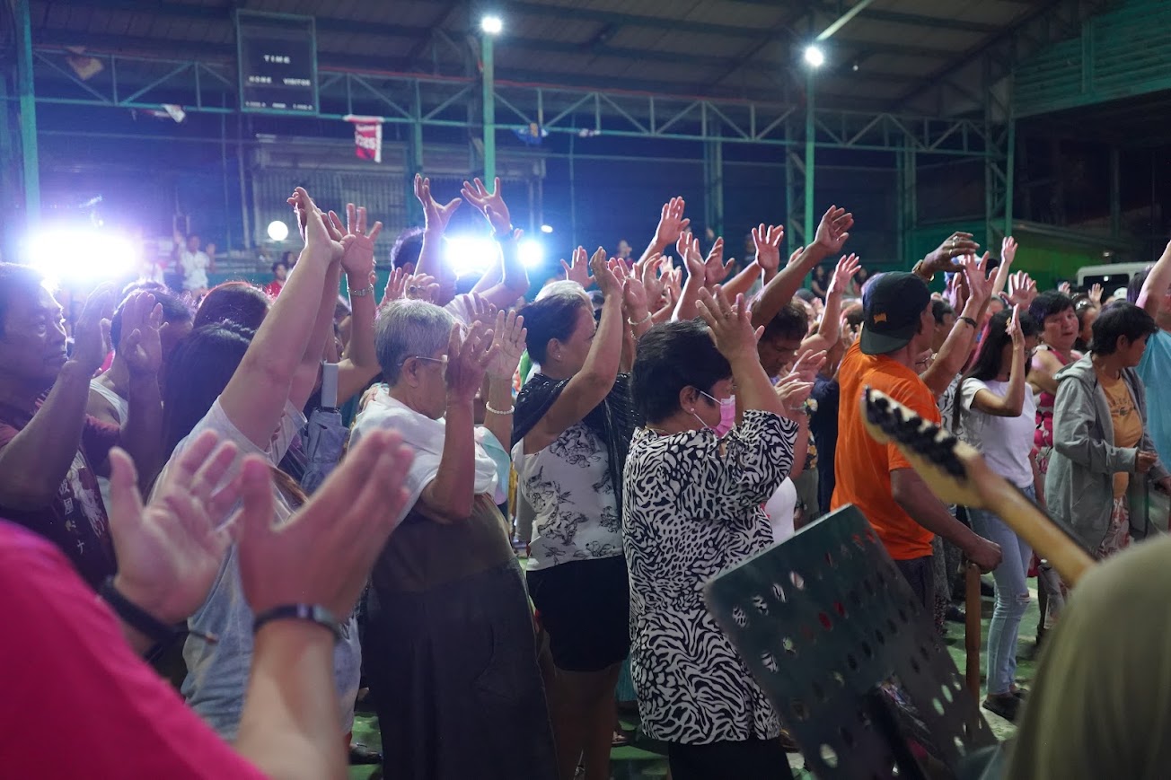 A sea of raised hands against the stage lights.