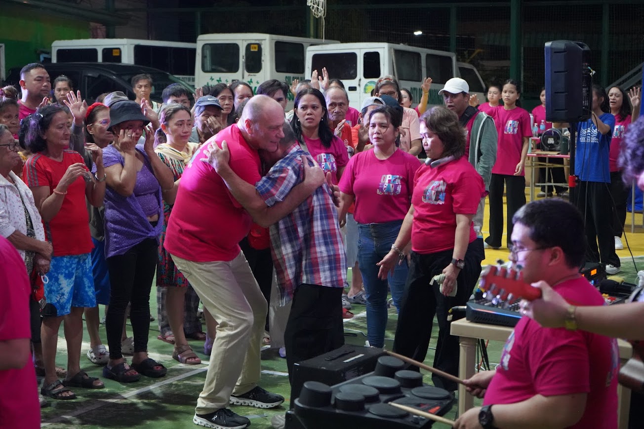 A team member embraces a community member as the crowd prays.
