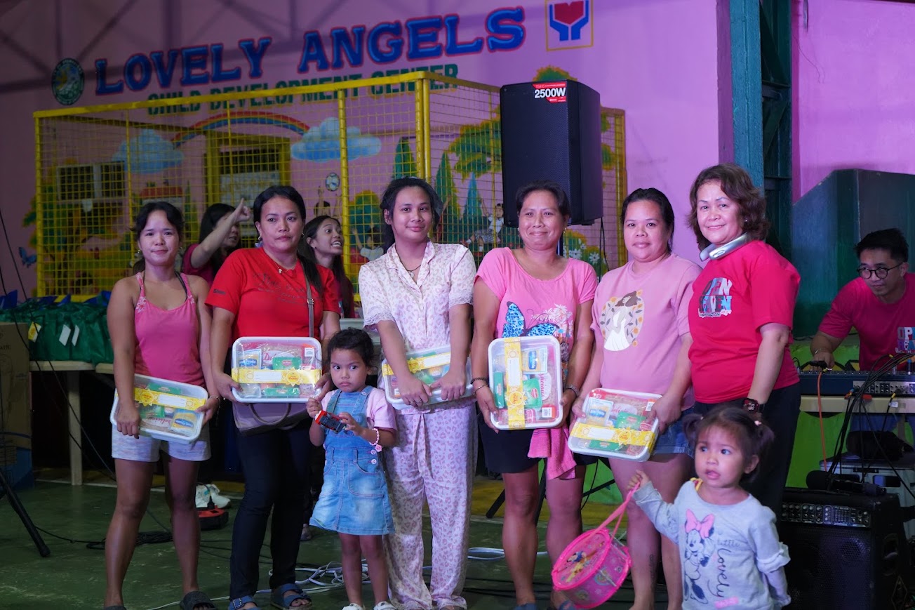 Six community members with food packs on stage.