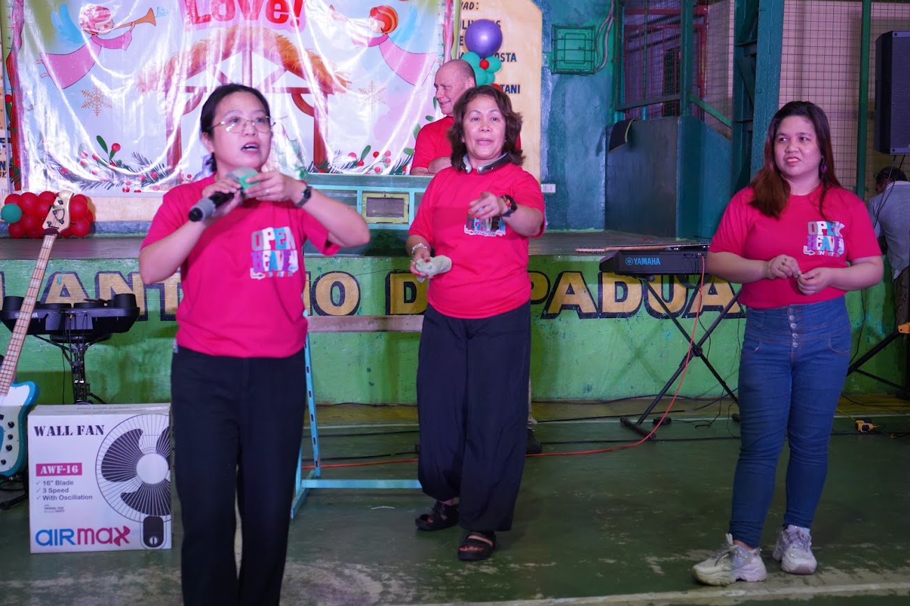 Rice cookers presented to two recipients, the team on stage behind.