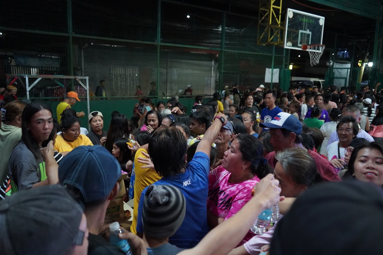 Evening distribution — the crowd packs the court under the lights.