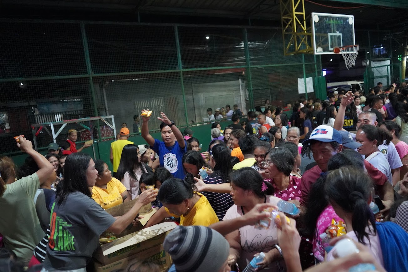 A dense line at the boxes, water bottles passed overhead.