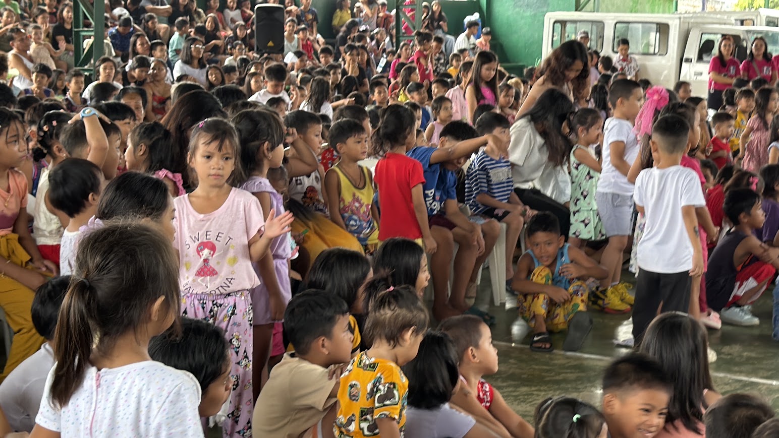 Close on the crowd — children in every direction.