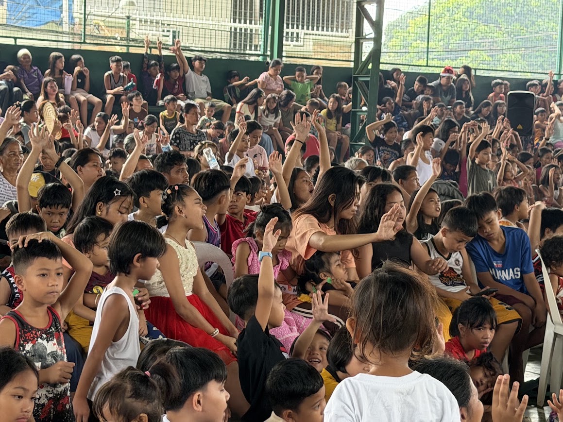 Hands lifted, children calling out toward the stage.