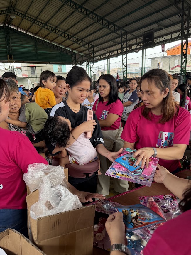 At the gift table, toys handed to a child in a mother's arms.