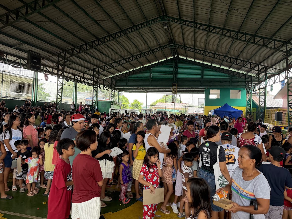 Children seated across the court, a team member standing among them.