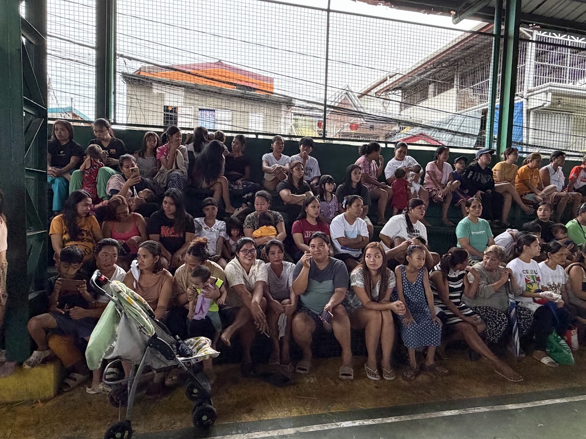 Mothers, children, and elders fill the stands, waiting for the program to begin.