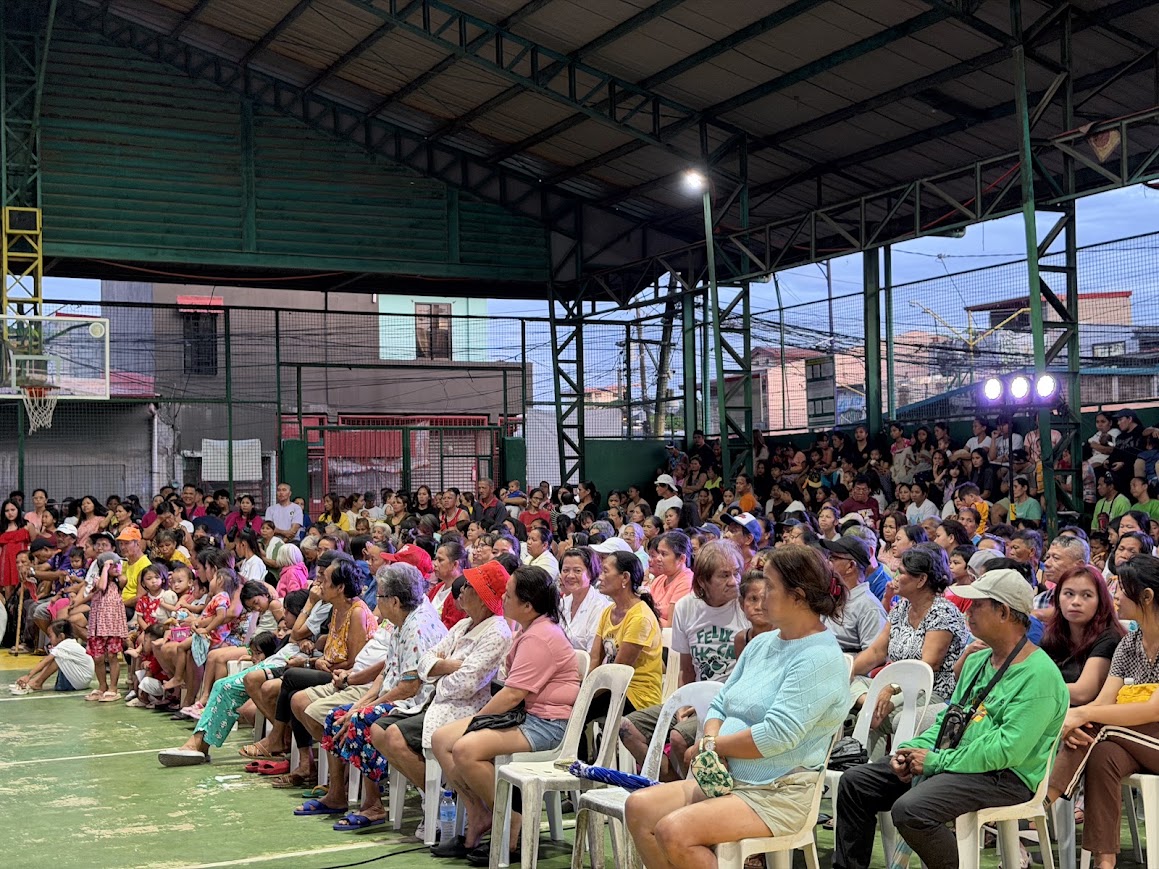A team member addresses the crowd from the front, the stands packed.