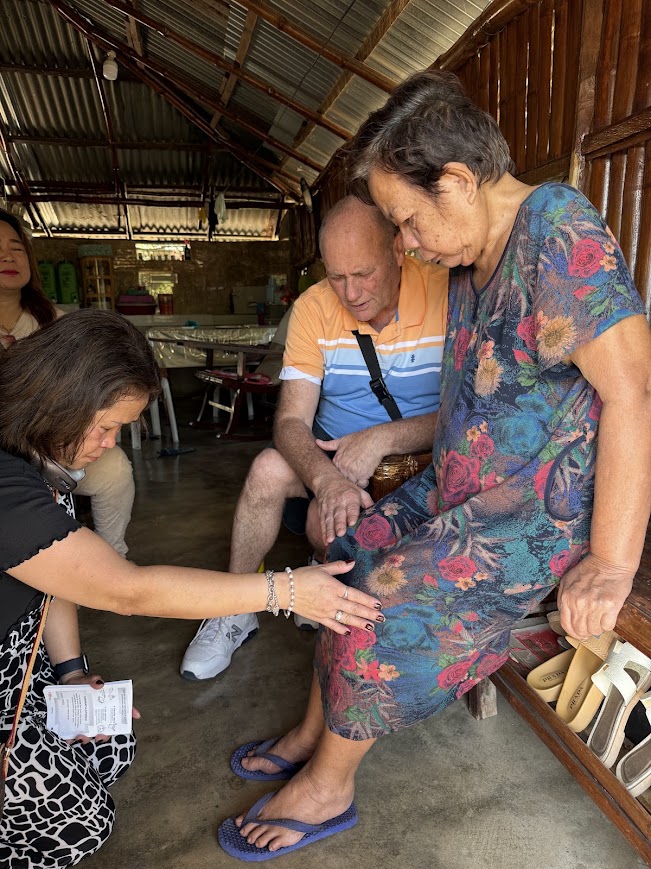 A morning home visit — prayer shared with a seated community member.