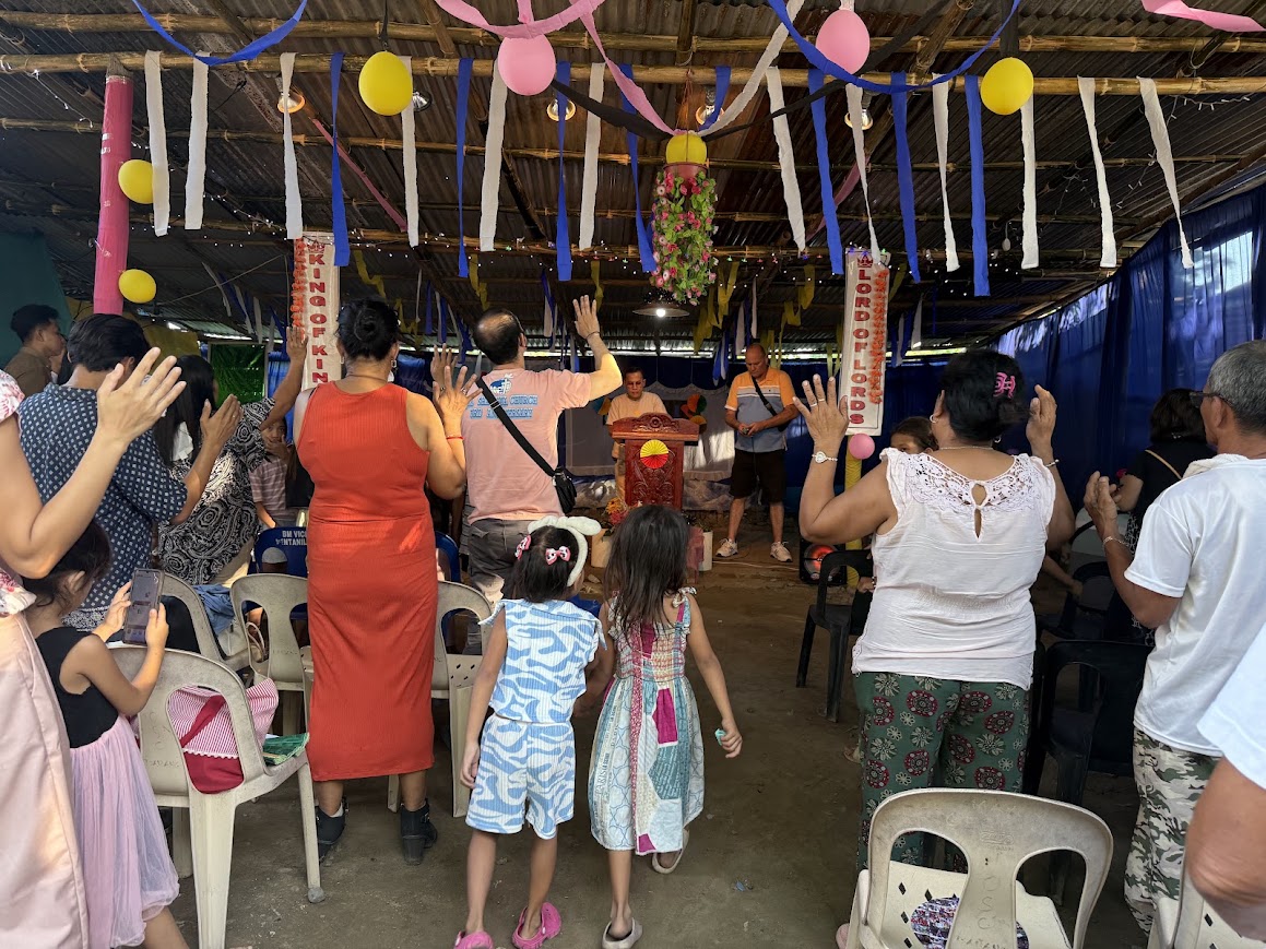 The congregation lifts their hands together in worship.
