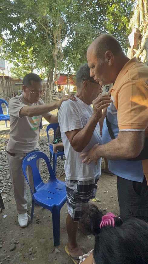 Prayer shared over a community member outdoors.
