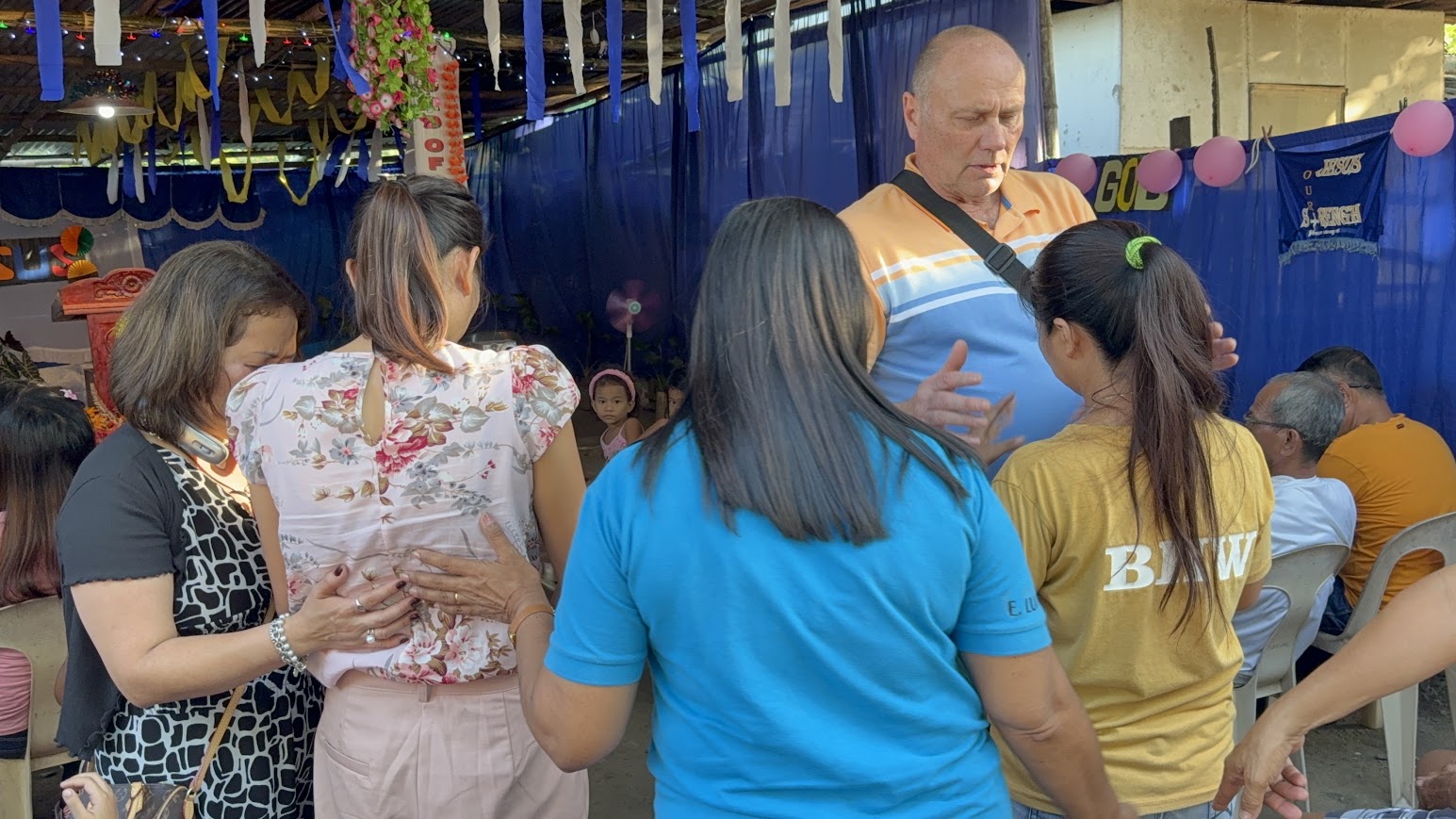 Several women join together in prayer for one of their own.
