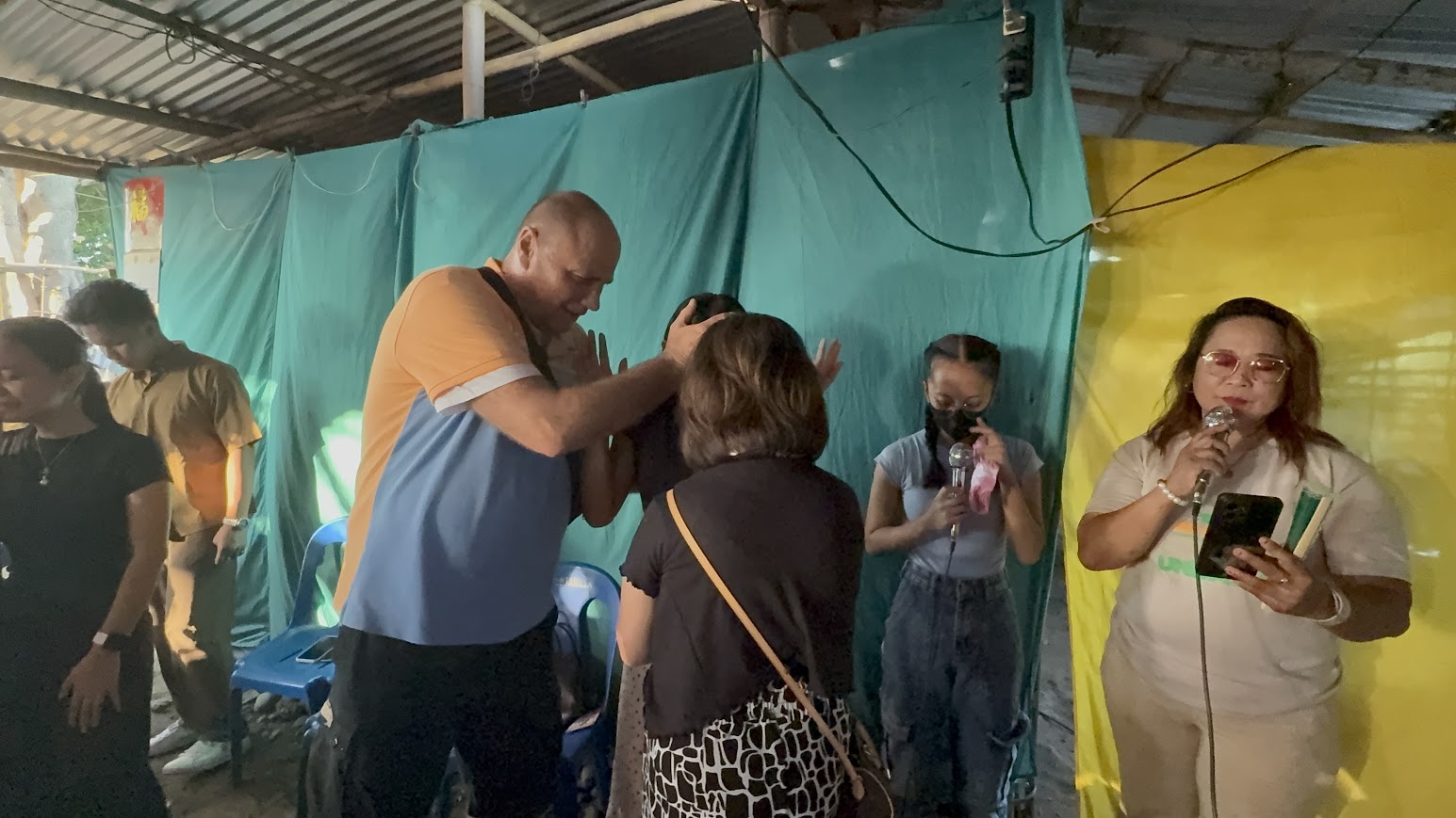 Hands laid in blessing over two community members.