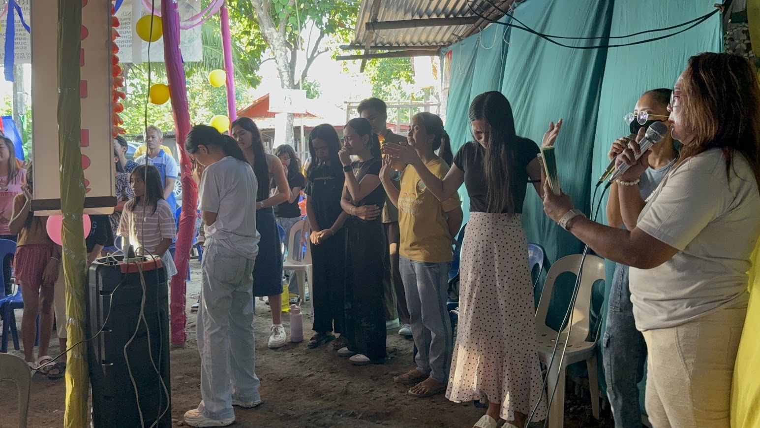 A worship leader sings as the congregation bows in prayer.