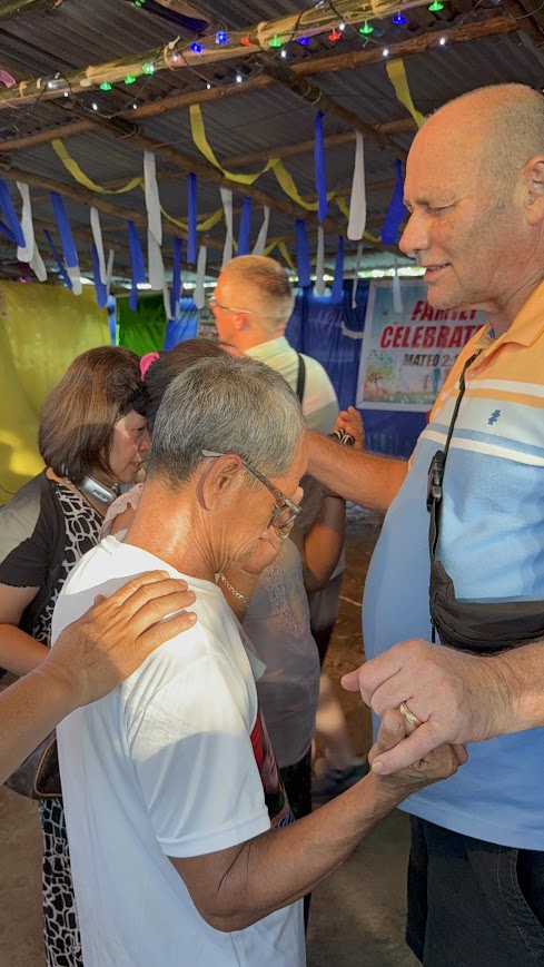 A hand of blessing rests on a community member's shoulder.