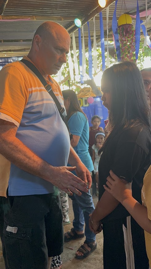 Two members of the ministry team pray together over a seated community member.