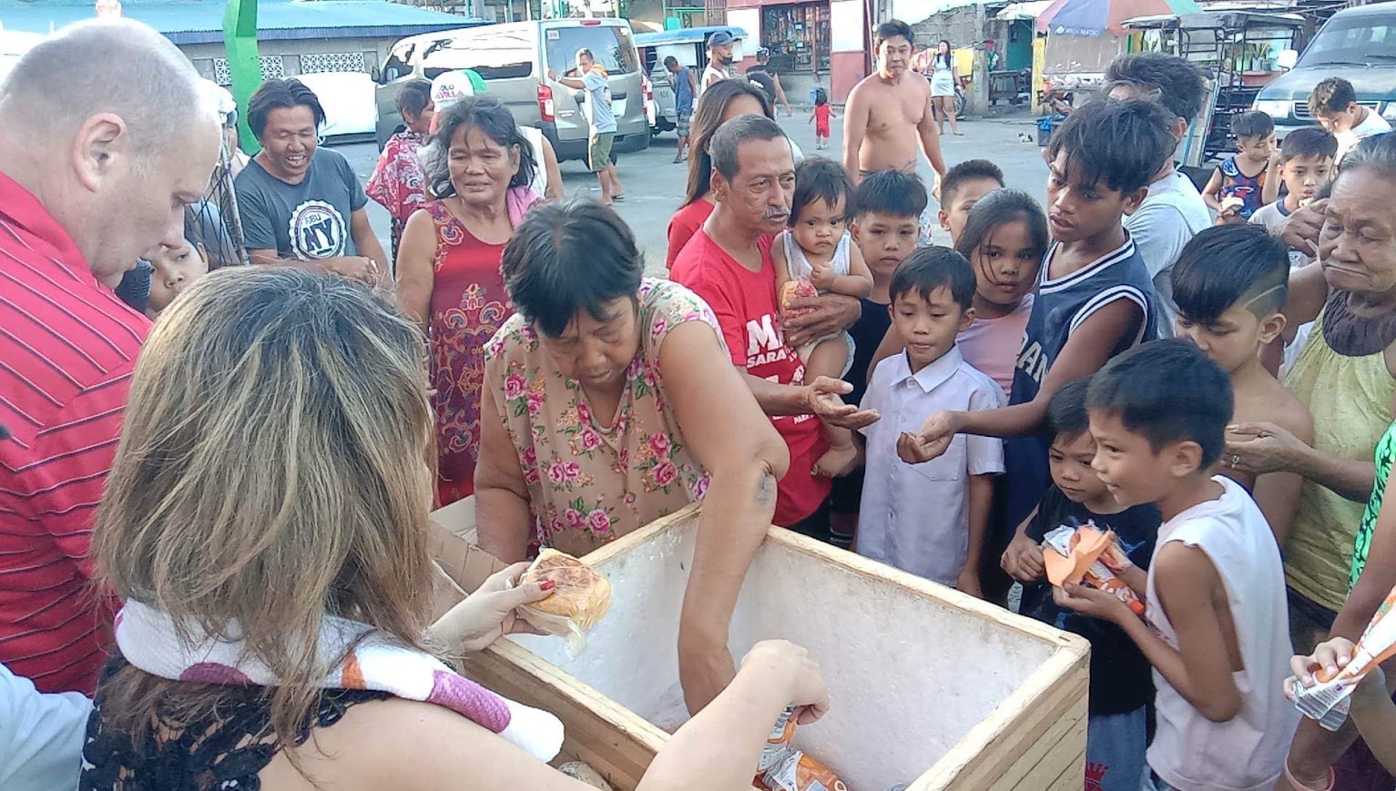 Bread handed across the cooler to a line of children and elders.