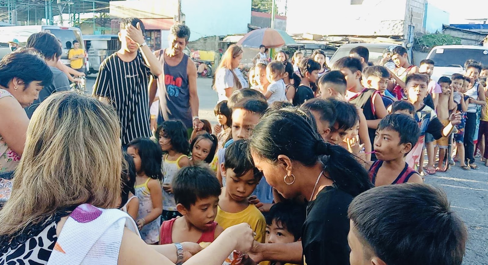 A long line of children waits as a team member hands out bread.