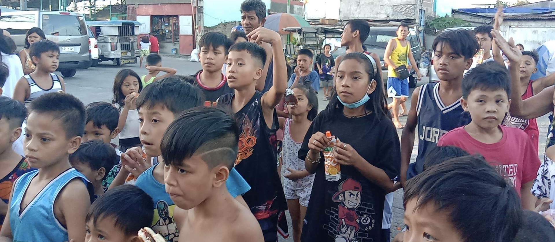 Children crowd in, one already holding a juice pouch.