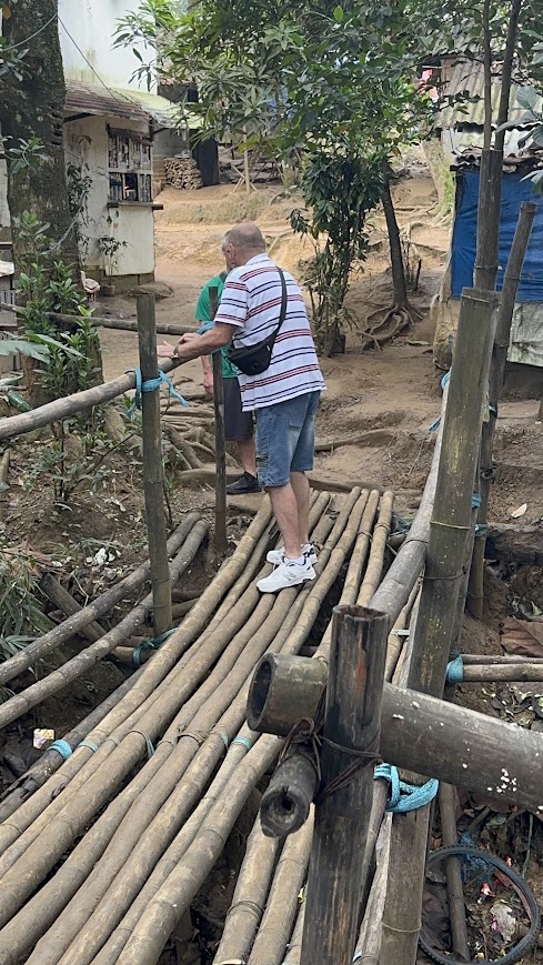 Two team members cross a bamboo footbridge into the barangay.