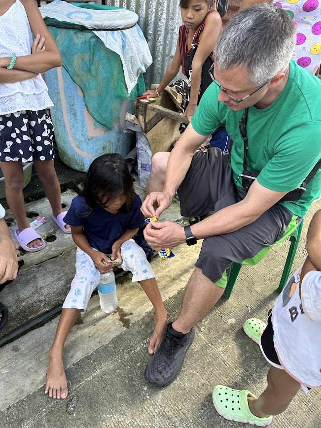 A team member helps a girl open a snack on the step.
