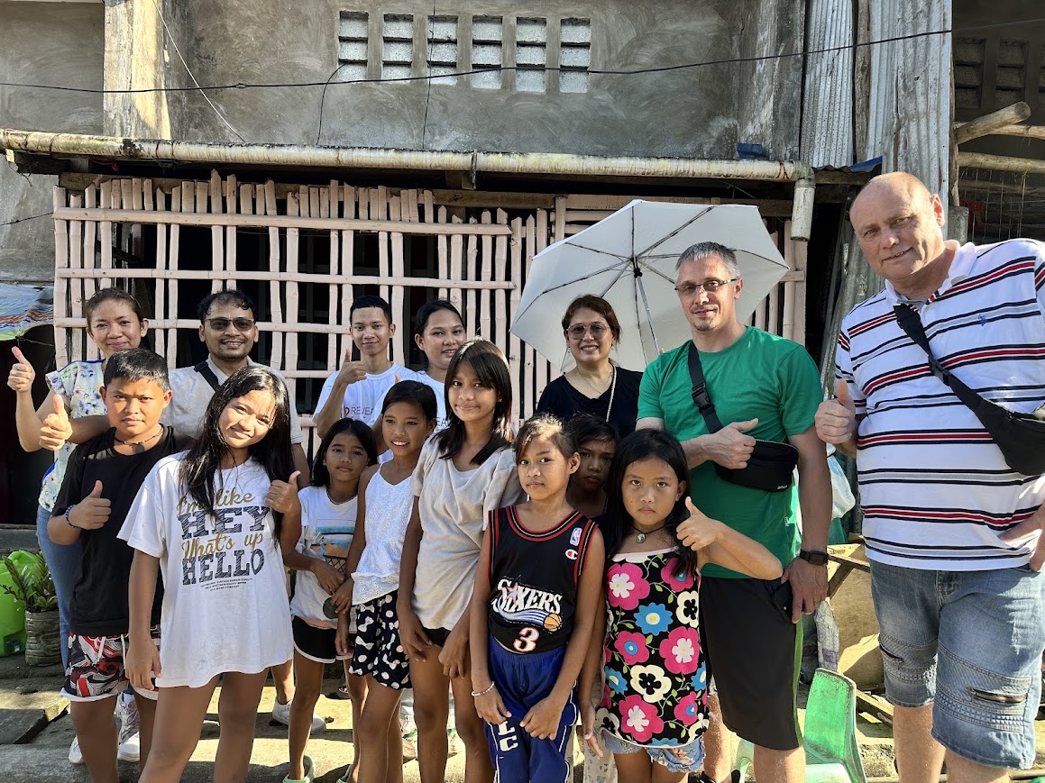 The team with a family in front of their bamboo-slat home.