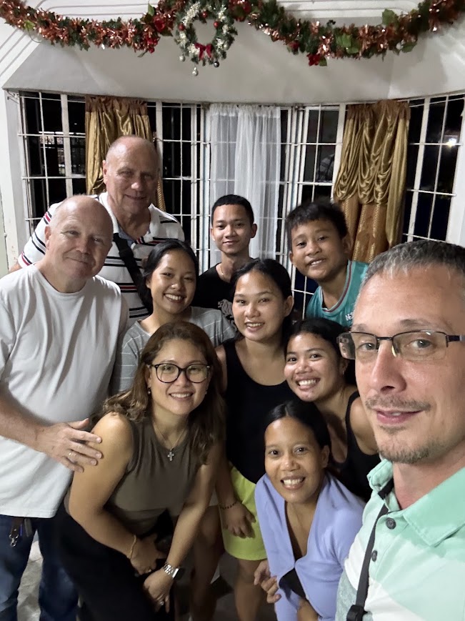 The team with the host family, a Christmas wreath overhead.