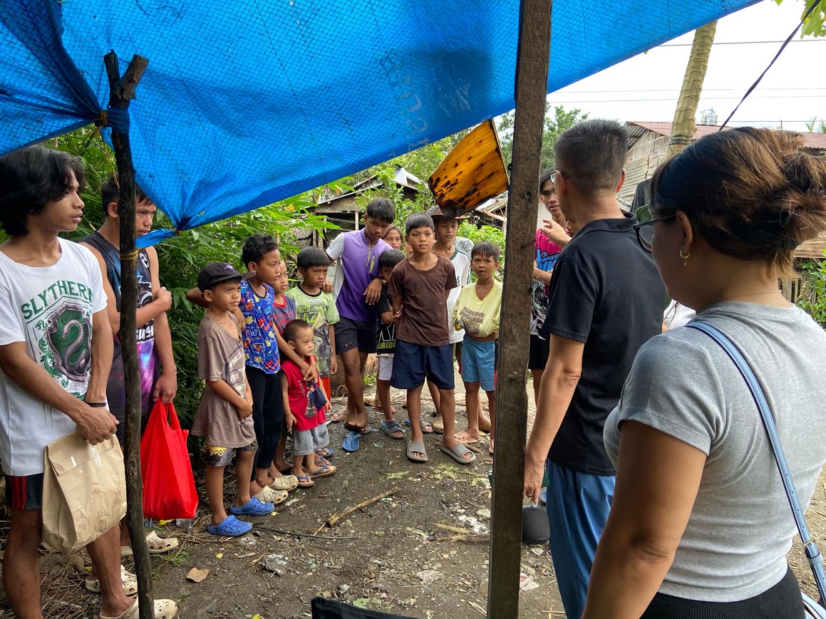 The boys and younger children line up along the tarp as the team arrives.