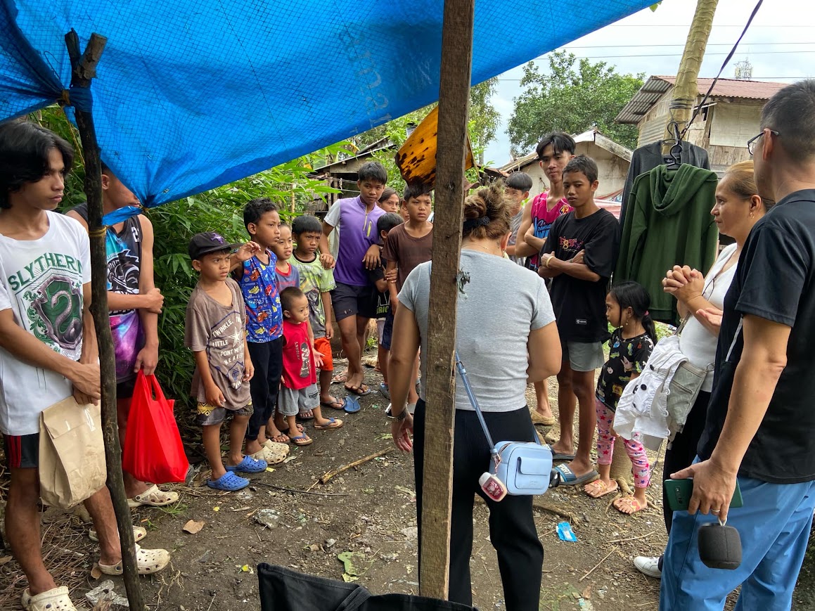 A team member speaks with the group, a young girl at the edge.