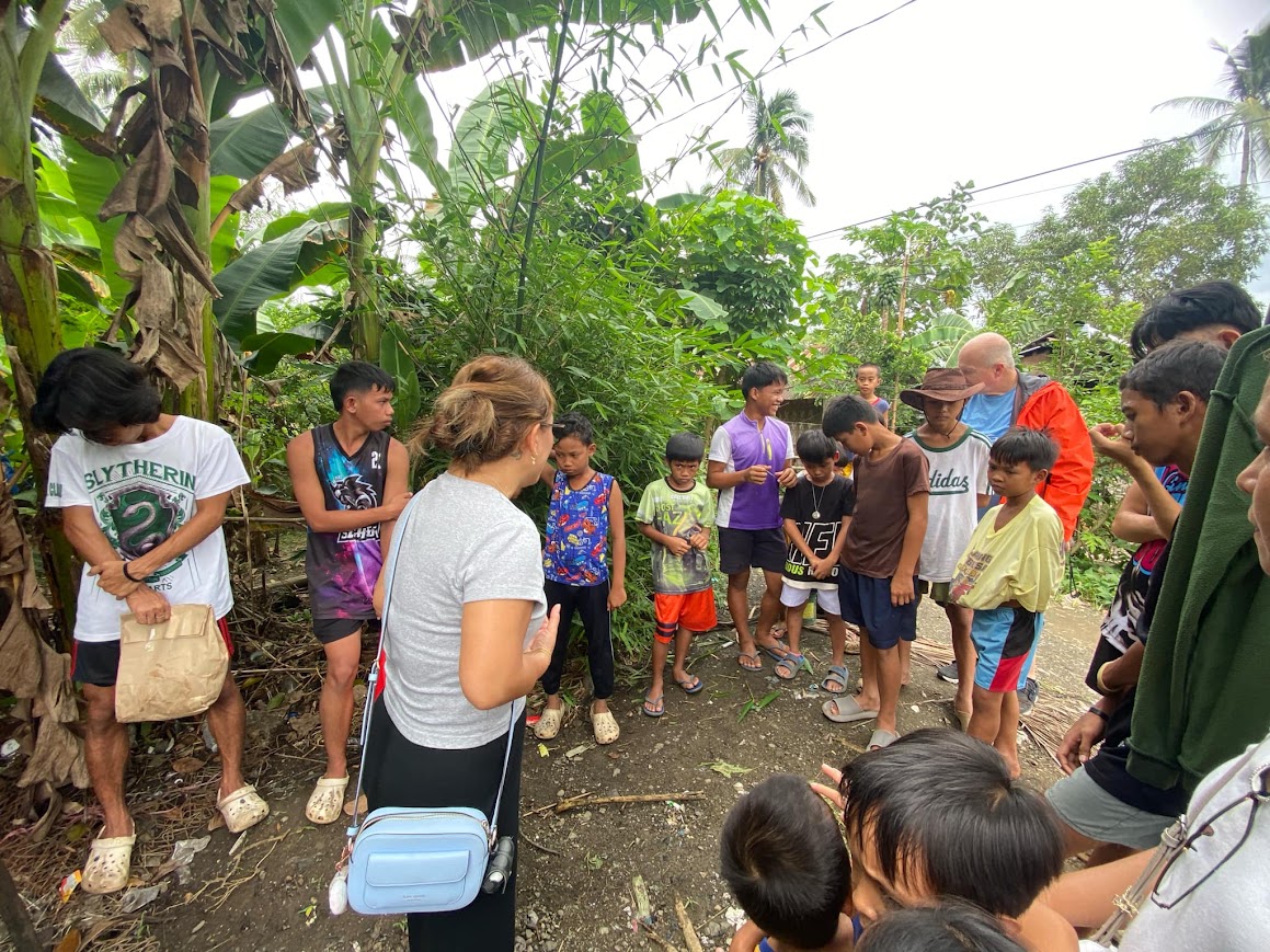 The team with the boys in the yard, banana trees behind.