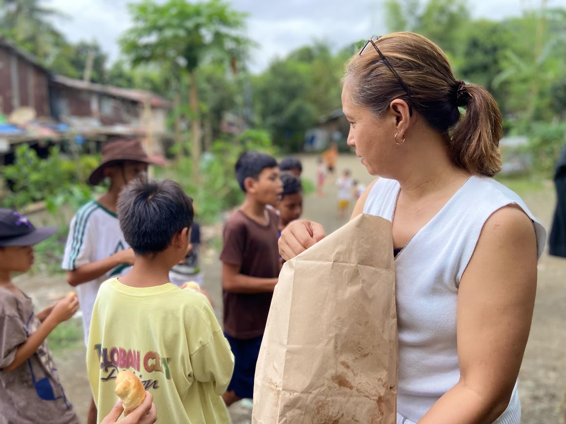 A team member with a bag of bread, a boy in a Tacloban City shirt at the front.
