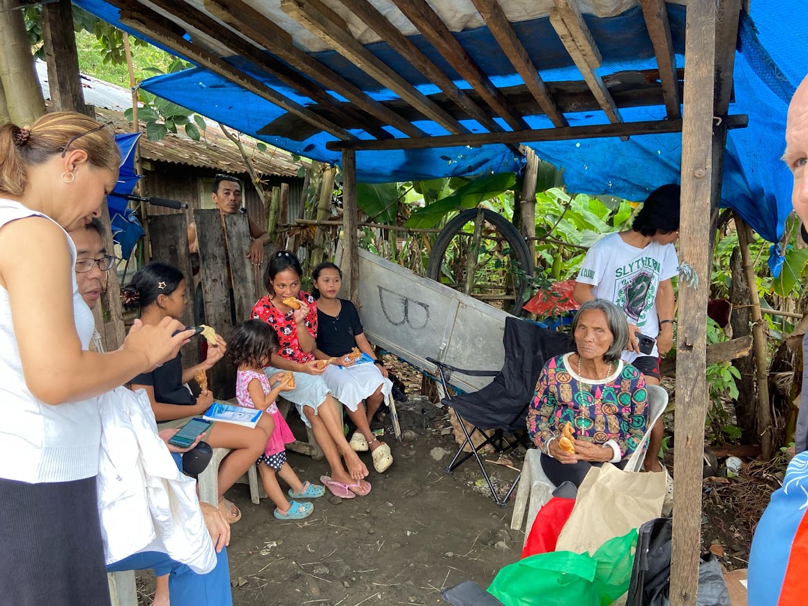 The family and the team share bread under the tarp.