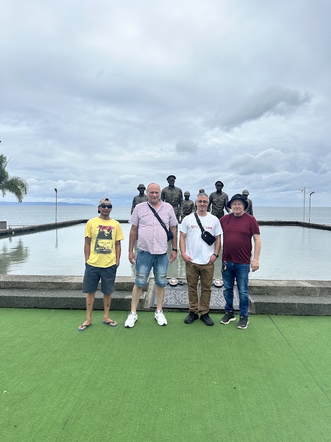 Four team members at the MacArthur Landing Memorial in Palo, Leyte Gulf behind.
