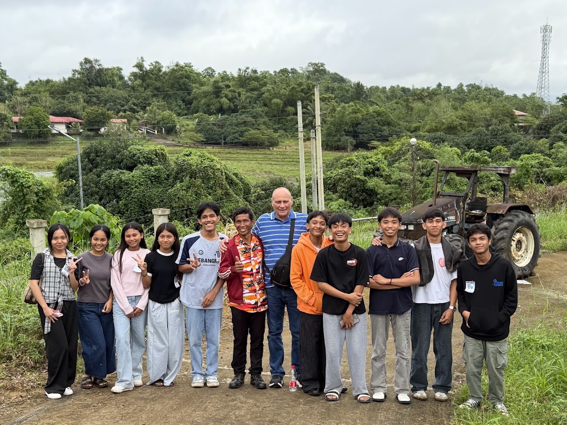 The team and youth leaders at the farm school the day before the event, rice fields behind them.