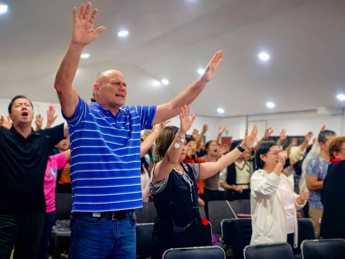 Worship — both hands raised, the whole room on its feet.