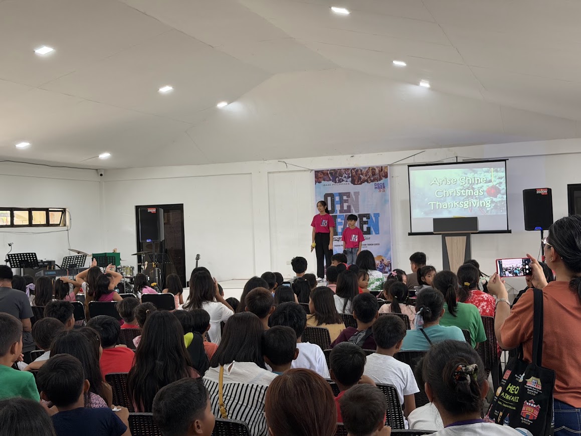 The audience faces the stage as a youth duet begins.