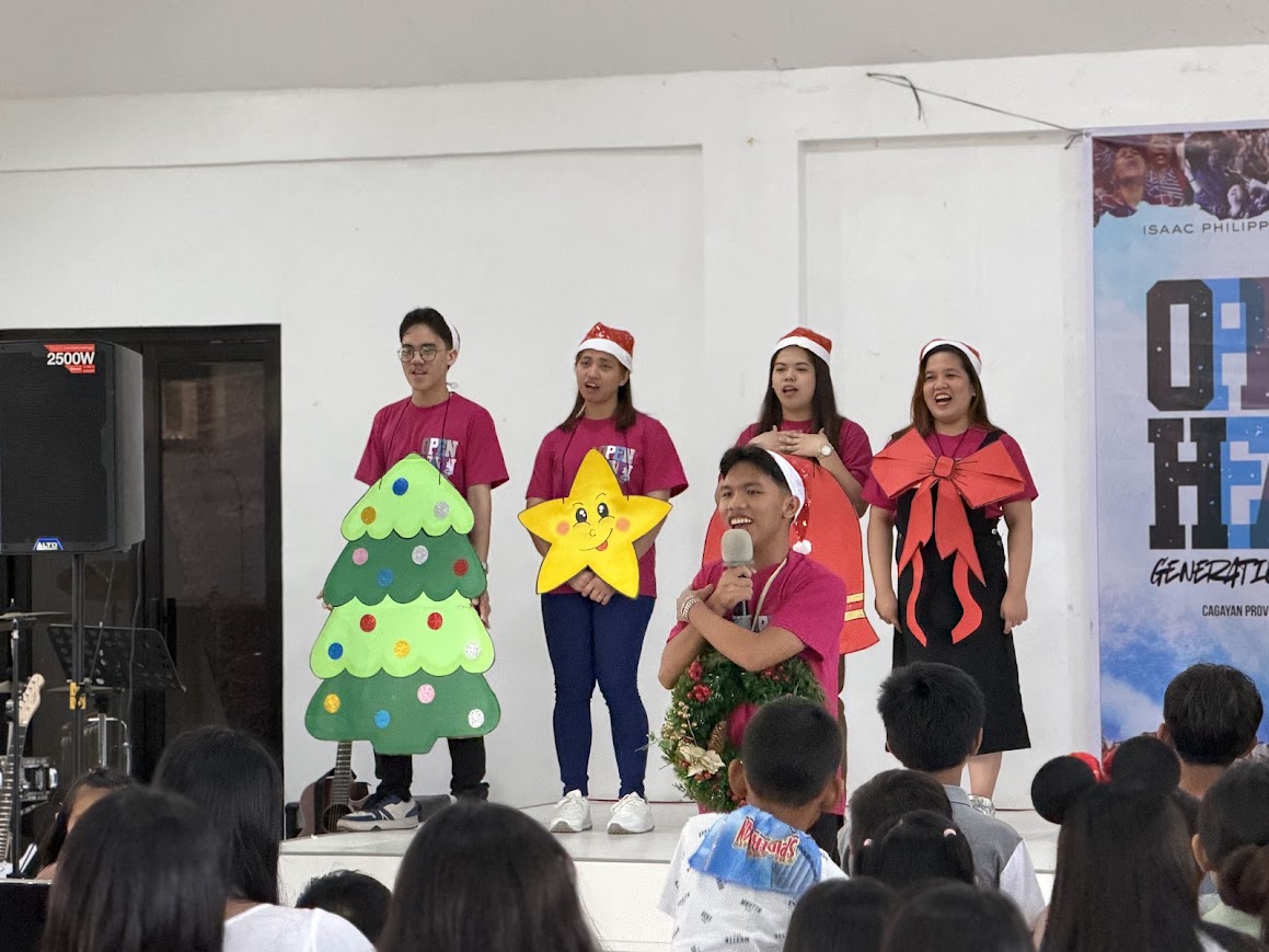 The cast sings together — tree, star, wreath, bell, and bow.