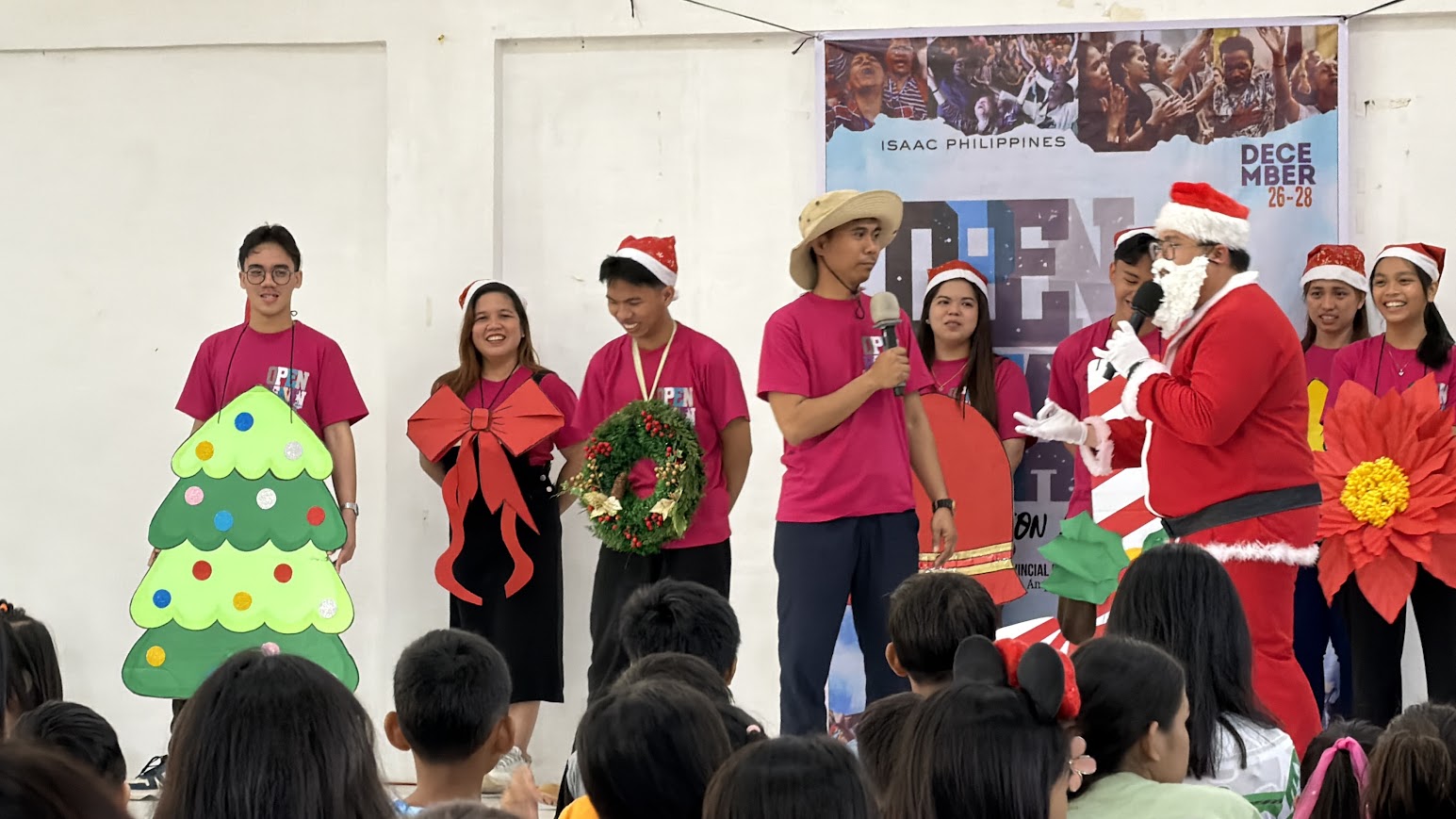 The Christmas skit — a tree, a bow, a wreath, and Santa with the mic.